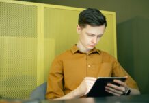 Młody mężczyzna w żółtej koszulce uczy się Excela na tablecie w domu