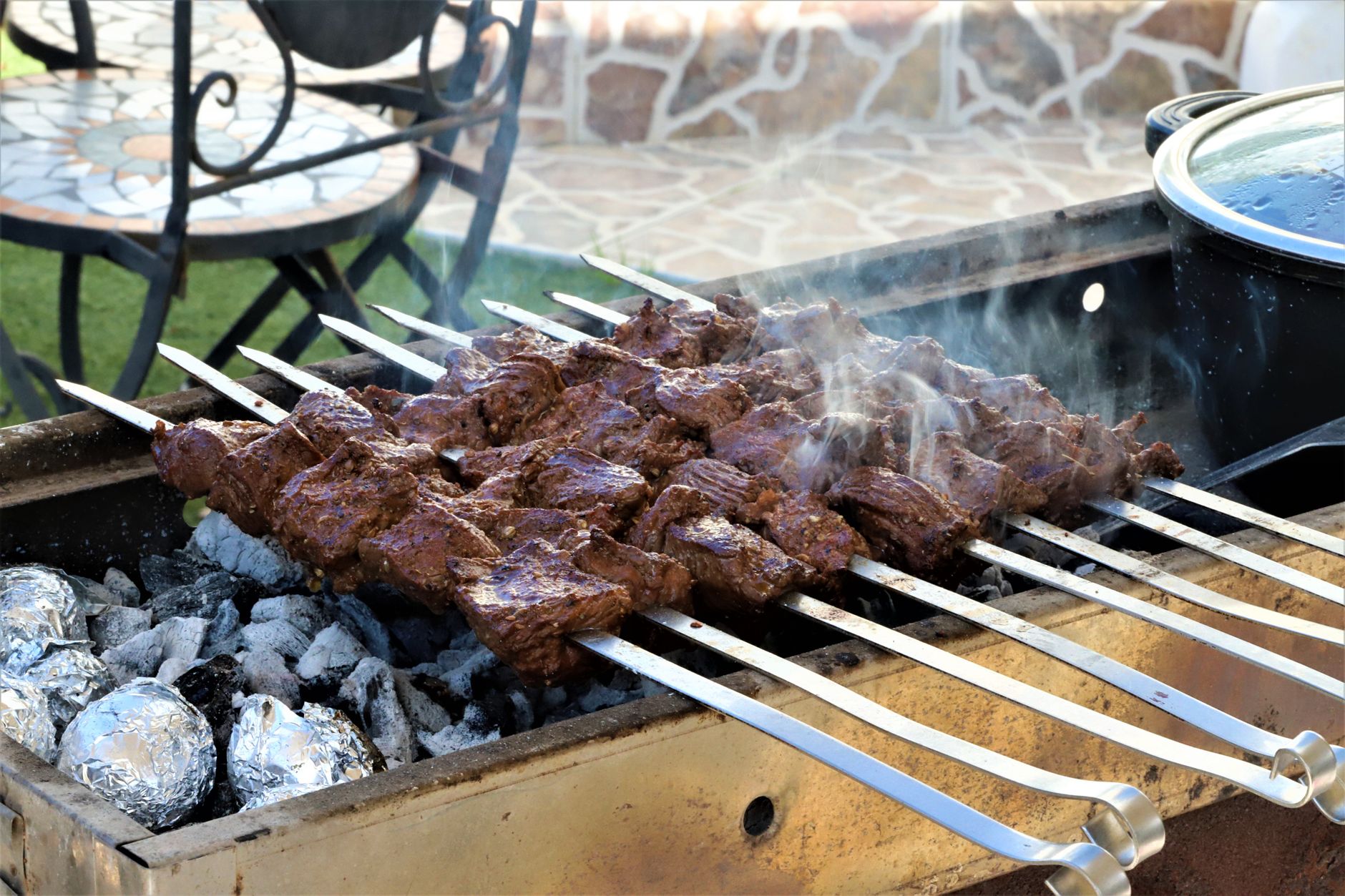 Szaszłyki piekące się na grillu węglowym podczas pikniku na pustyni